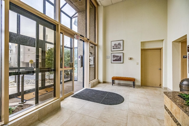 interior space with light tile patterned flooring, a high ceiling, and baseboards