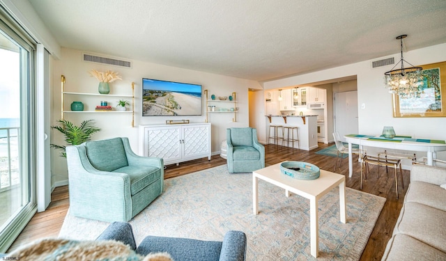 living room featuring a textured ceiling, visible vents, wood finished floors, and a healthy amount of sunlight