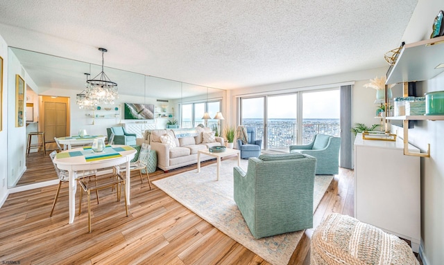 living room featuring a textured ceiling, a chandelier, and light wood-style floors