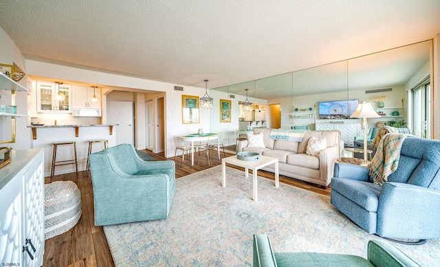 living area featuring a textured ceiling, visible vents, and wood finished floors