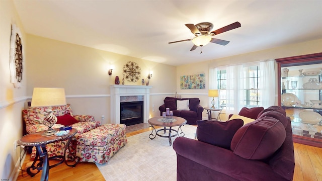 living area with light wood-style flooring, a high end fireplace, and ceiling fan