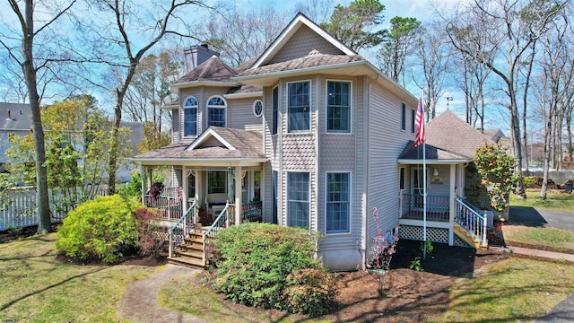 victorian home featuring a chimney, a front yard, and covered porch