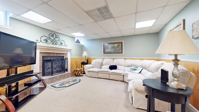 living area featuring wainscoting, a drop ceiling, a tile fireplace, carpet flooring, and visible vents