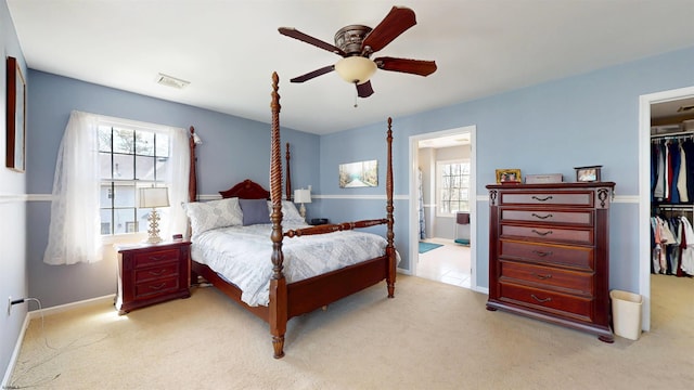 bedroom featuring a spacious closet, a closet, light colored carpet, and multiple windows