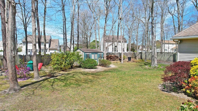 view of yard with a fenced backyard, a storage unit, an outdoor structure, and a residential view