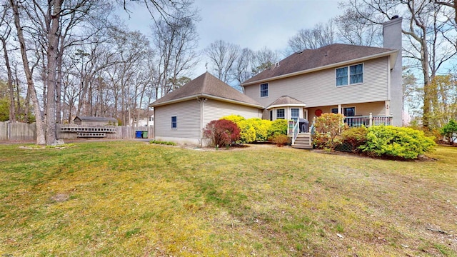 view of front of property with a chimney, fence, a wooden deck, roof with shingles, and a front yard