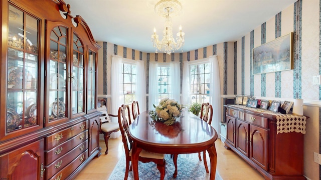 dining space with wallpapered walls, a wealth of natural light, and a chandelier