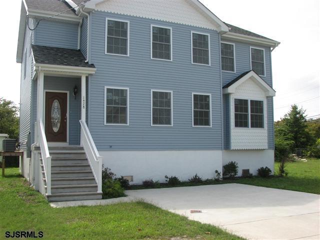 view of front of home with a patio, a front lawn, and a shingled roof
