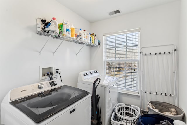 clothes washing area with washing machine and dryer, visible vents, and laundry area