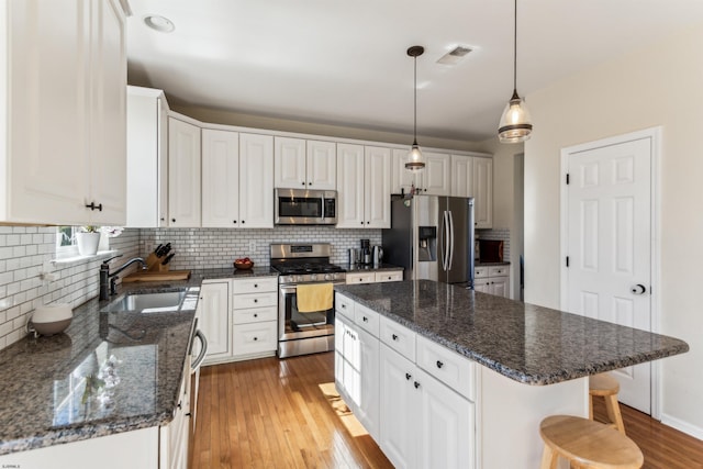 kitchen with backsplash, visible vents, appliances with stainless steel finishes, and a sink