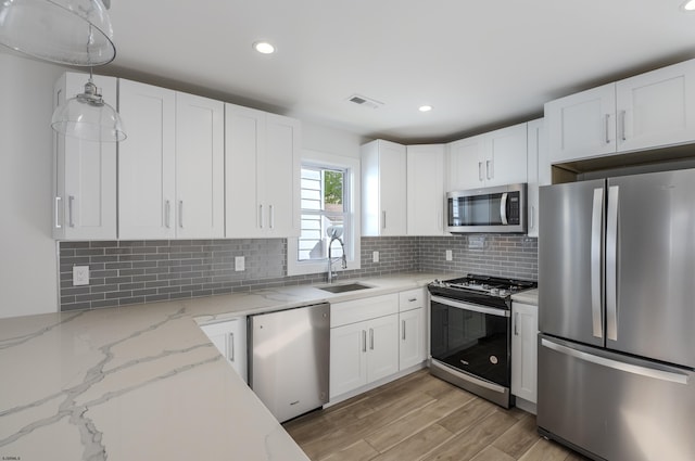 kitchen with light wood-style flooring, a sink, visible vents, white cabinetry, and appliances with stainless steel finishes