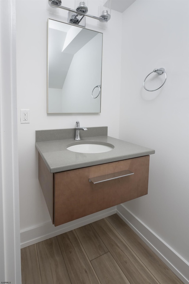 bathroom with baseboards, vanity, and wood finished floors