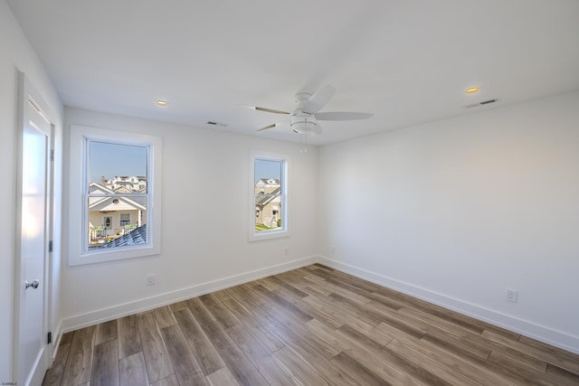 unfurnished room with wood finished floors, visible vents, and a wealth of natural light