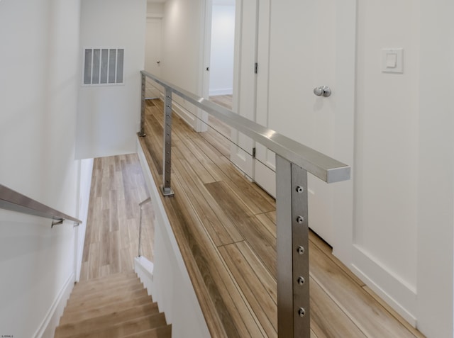 stairs with wood finished floors and visible vents