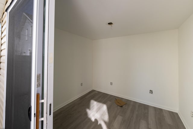 empty room featuring baseboards and dark wood-style floors