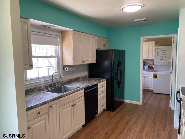 kitchen with dark wood-style floors, dark countertops, a sink, black appliances, and visible vents