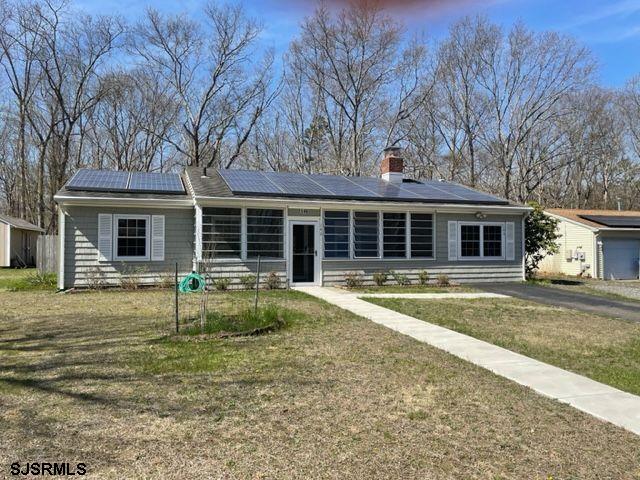 view of front of house featuring solar panels, a front yard, and a chimney