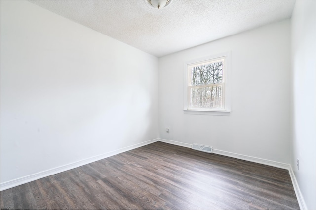 spare room featuring baseboards, visible vents, a textured ceiling, and dark wood-type flooring