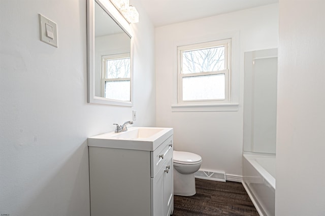 bathroom with wood finished floors, vanity, baseboards, toilet, and visible vents