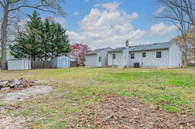 rear view of house featuring a storage shed, a lawn, a chimney, an outdoor structure, and cooling unit