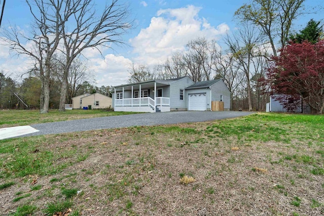 view of front of home with an attached garage, driveway, a front yard, and covered porch