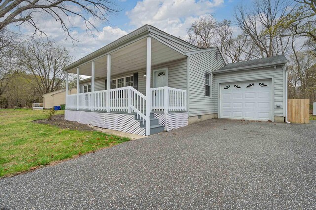 view of front of property featuring aphalt driveway, a front lawn, crawl space, covered porch, and a garage