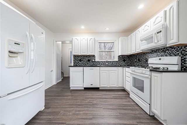 kitchen with a sink, dark countertops, white cabinetry, decorative backsplash, and white appliances