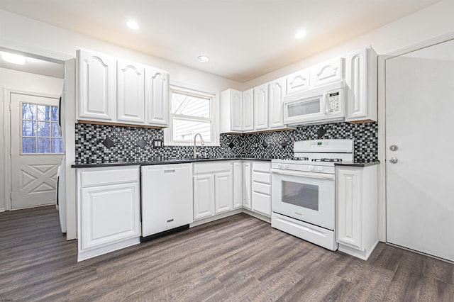 kitchen featuring dark countertops, white appliances, a sink, and dark wood-style floors