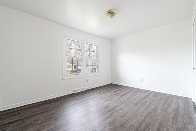 empty room featuring dark wood-style floors, baseboards, and visible vents