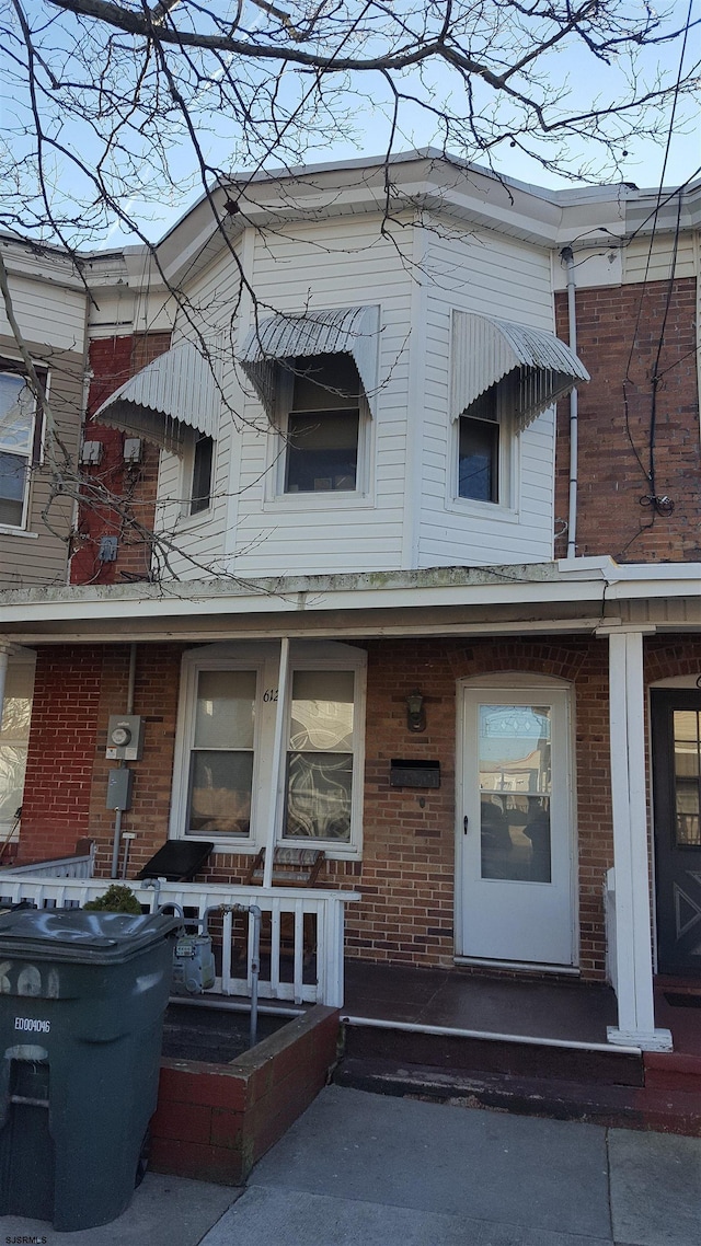 view of property with covered porch and brick siding