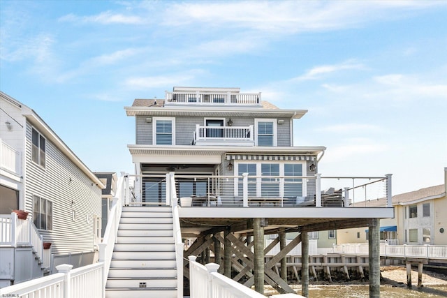 coastal inspired home with stairway, fence, and a water view