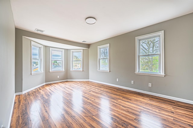 unfurnished room featuring baseboards, wood finished floors, and visible vents