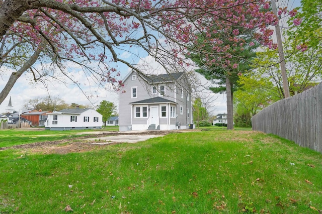 back of property featuring a lawn and fence