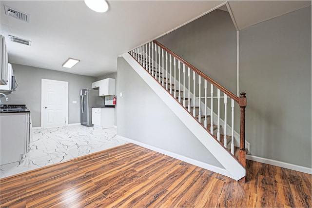 stairway with baseboards, visible vents, and marble finish floor