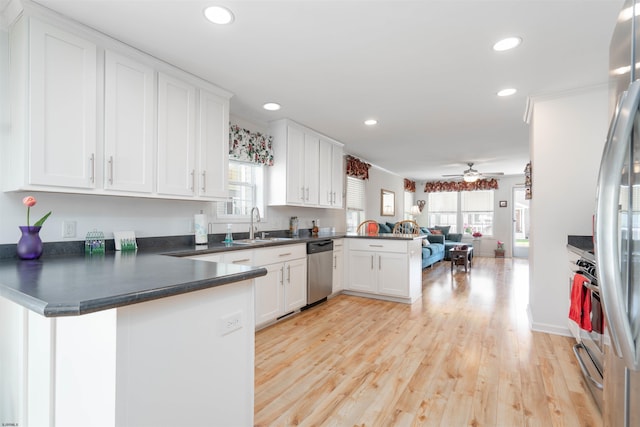 kitchen with dark countertops, a peninsula, open floor plan, and white cabinetry