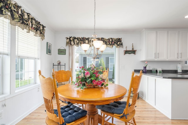 dining space featuring light wood-type flooring, baseboards, and a chandelier