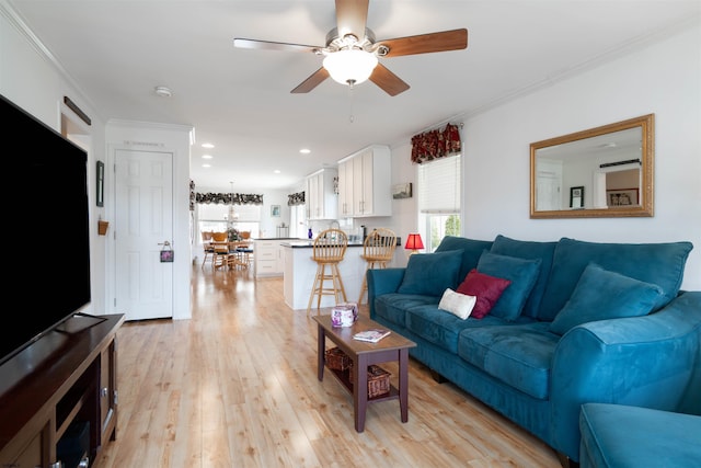 living room featuring a wealth of natural light, a ceiling fan, crown molding, and light wood finished floors