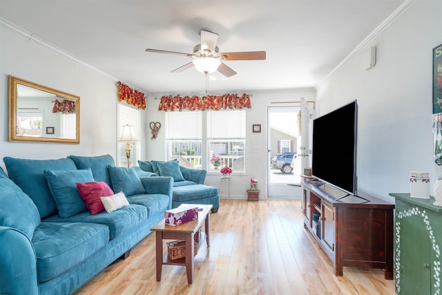 living area featuring crown molding, light wood-type flooring, a ceiling fan, and baseboards