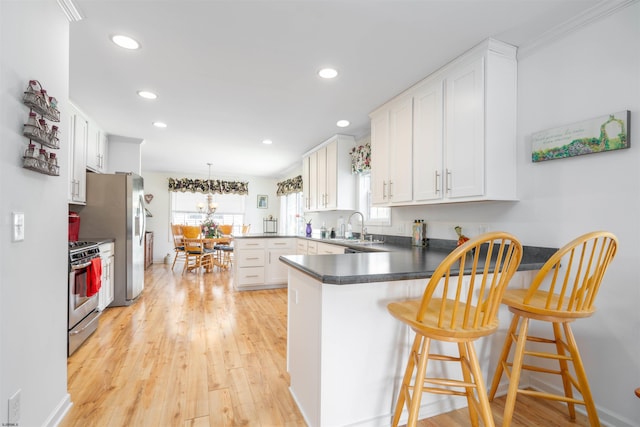 kitchen with a peninsula, white cabinets, stainless steel appliances, and recessed lighting