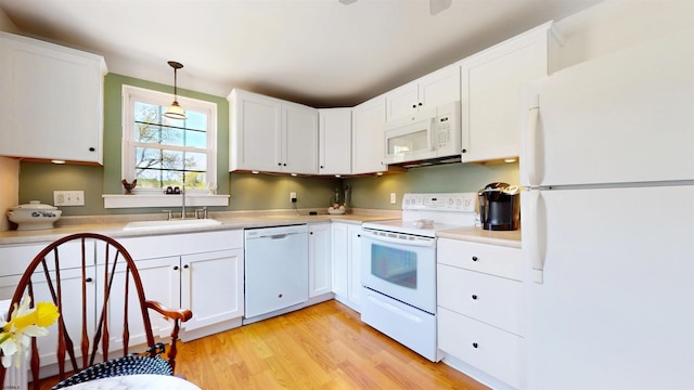 kitchen with light wood-style flooring, a sink, white cabinetry, white appliances, and light countertops