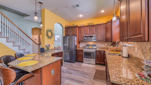 kitchen with a sink, arched walkways, stainless steel appliances, a peninsula, and visible vents