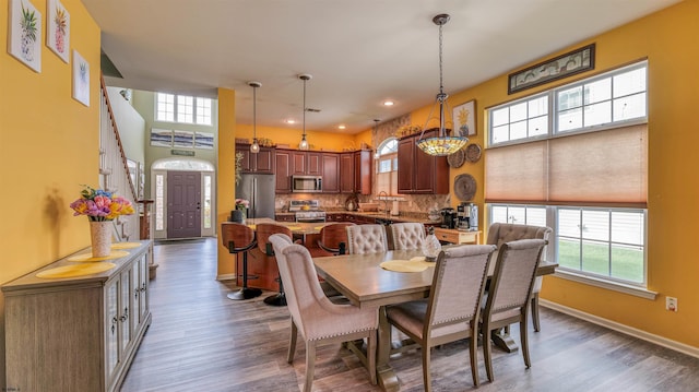 dining space with baseboards, wood finished floors, recessed lighting, and stairs