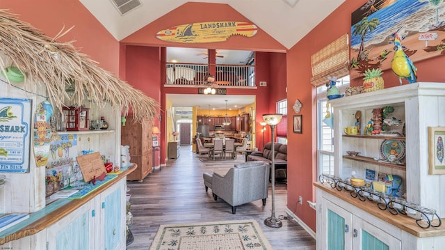 interior space featuring baseboards, wood finished floors, visible vents, and high vaulted ceiling