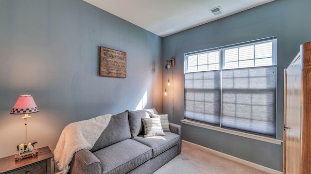 living area with baseboards, visible vents, and carpet