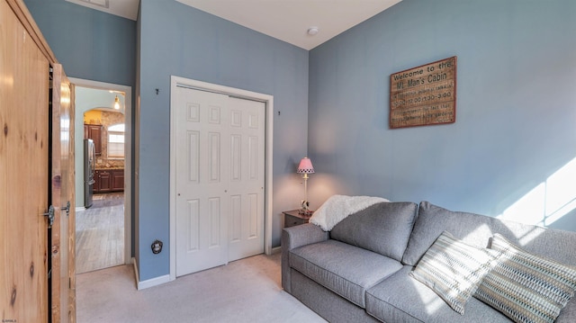 living room with light colored carpet, arched walkways, and baseboards