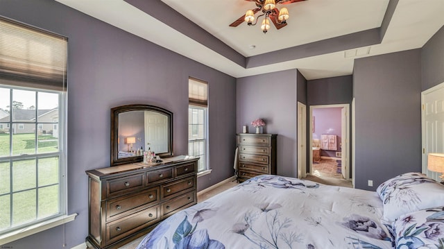 bedroom featuring a tray ceiling, ceiling fan, baseboards, and light carpet