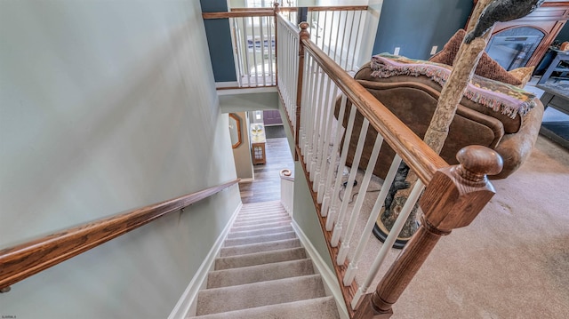 stairway with baseboards and carpet floors