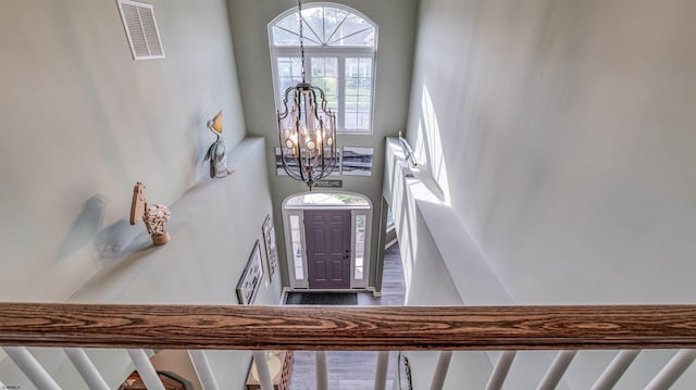foyer with a high ceiling, an inviting chandelier, stairs, and visible vents