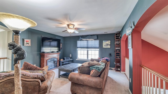 living room with light colored carpet, ceiling fan, baseboards, and a glass covered fireplace
