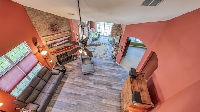 living room featuring a ceiling fan, a large fireplace, wood finished floors, and visible vents
